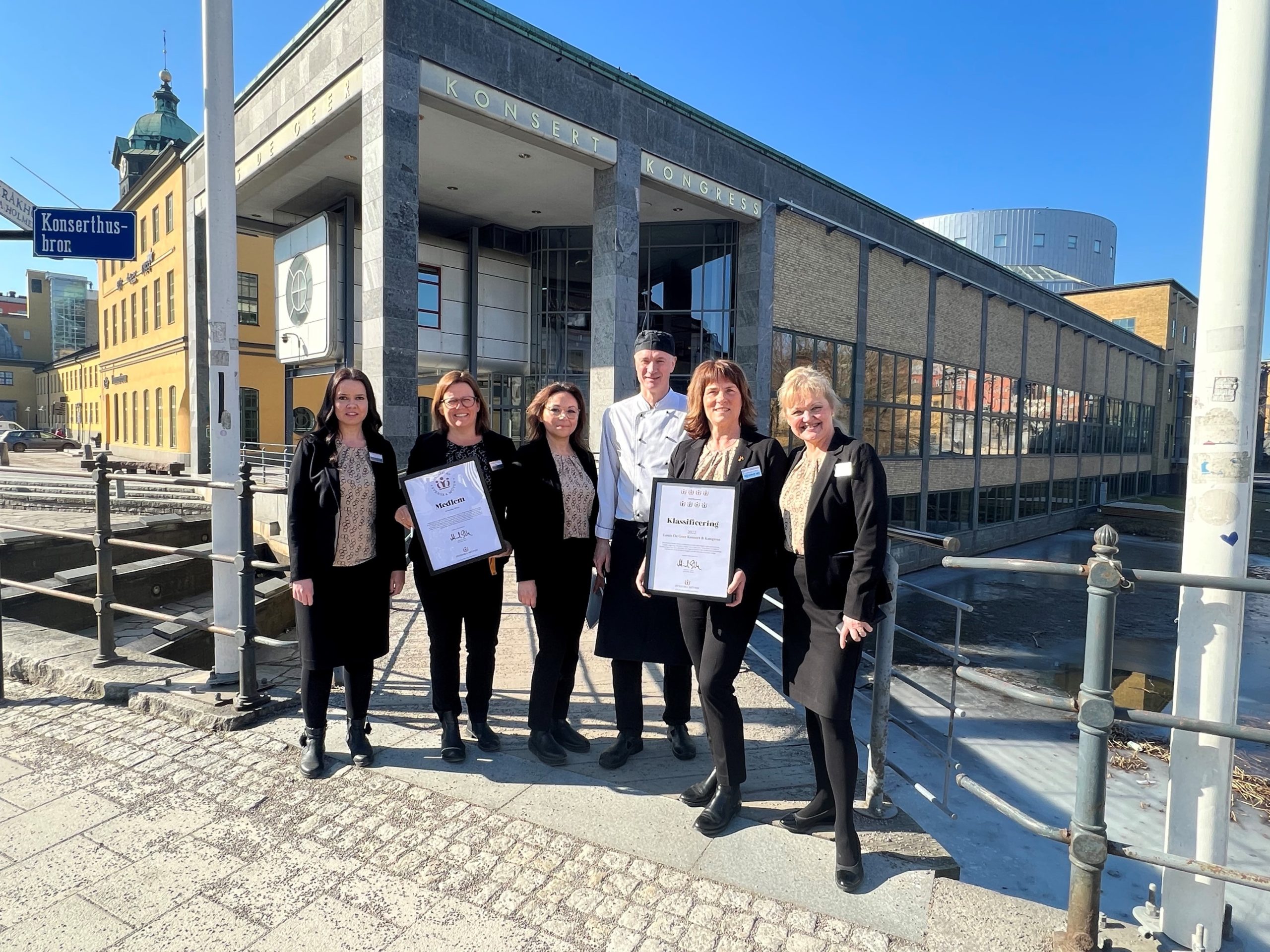 Personer utanför byggnad med diplom