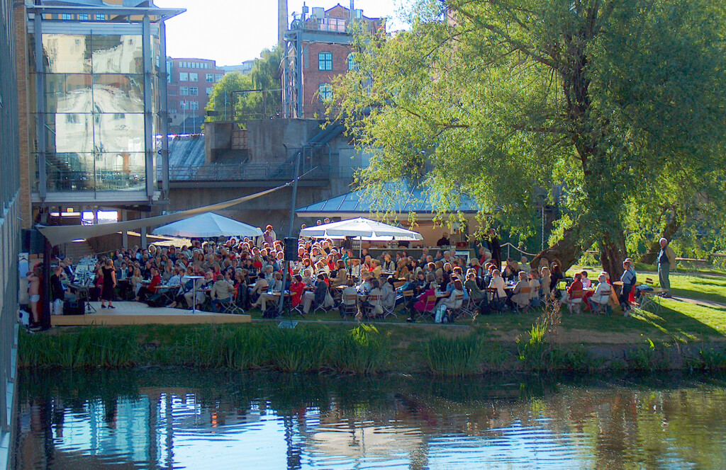 En grön holme fullt med personer framför en liten scen