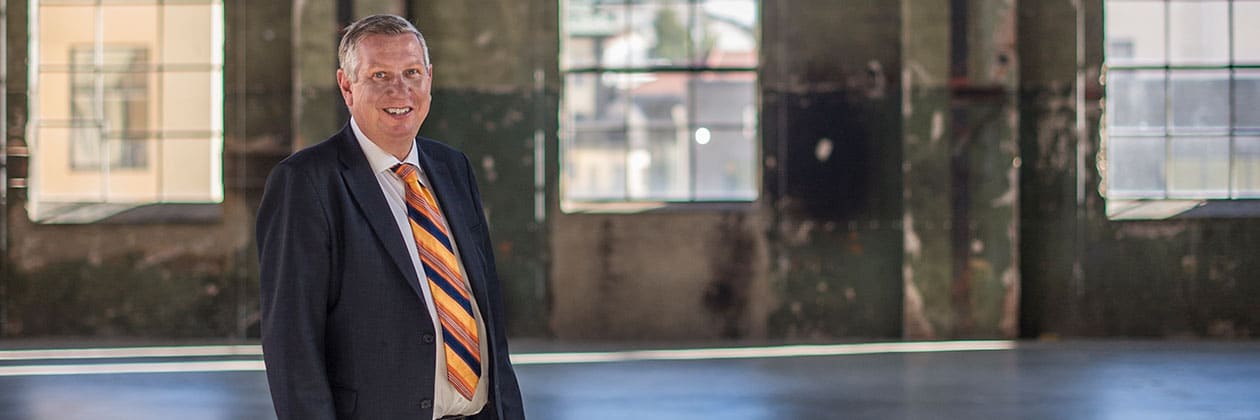 Man i kostym och orange randig slips