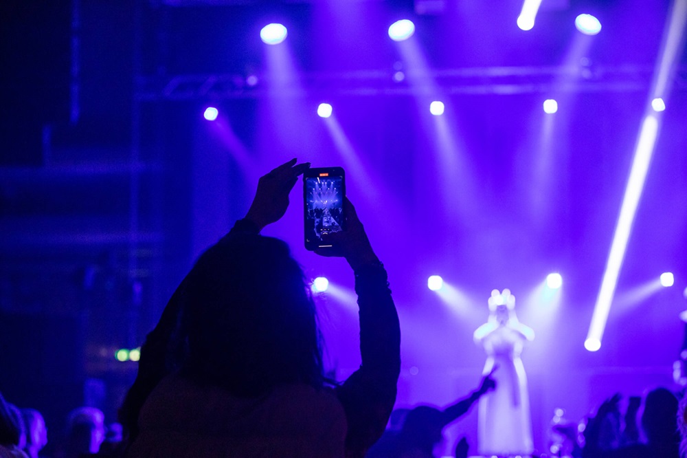 Siluett av en person som tar bild på en konsert. 